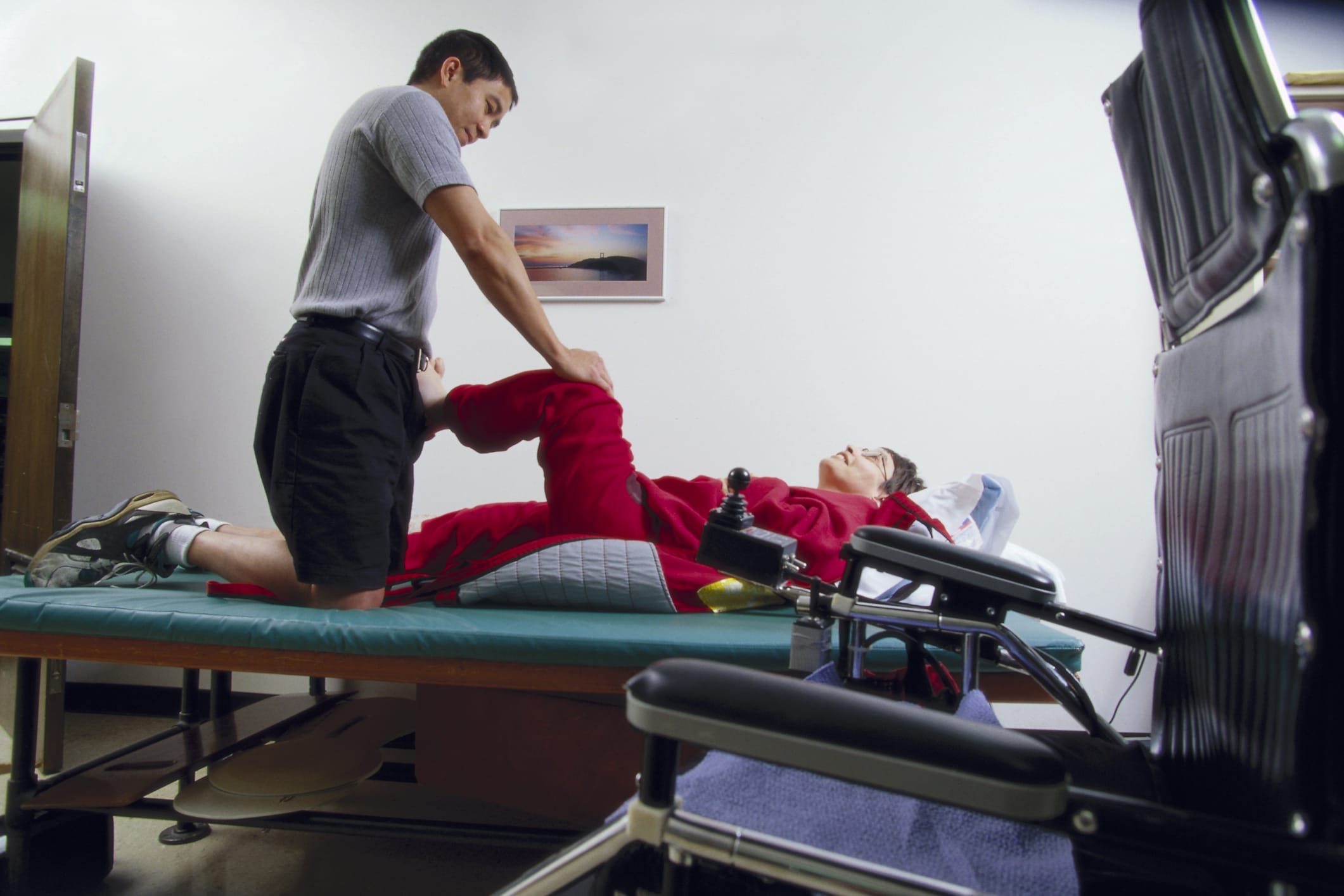 person with sever spasticity stretching with support from a physical therapist