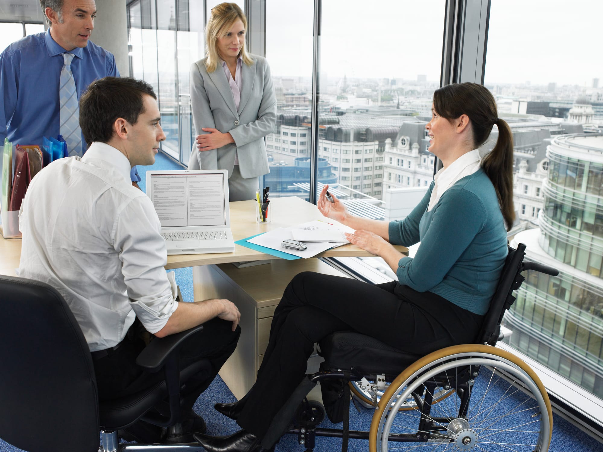 women in a wheelchair talking to work colleagues in an office setting