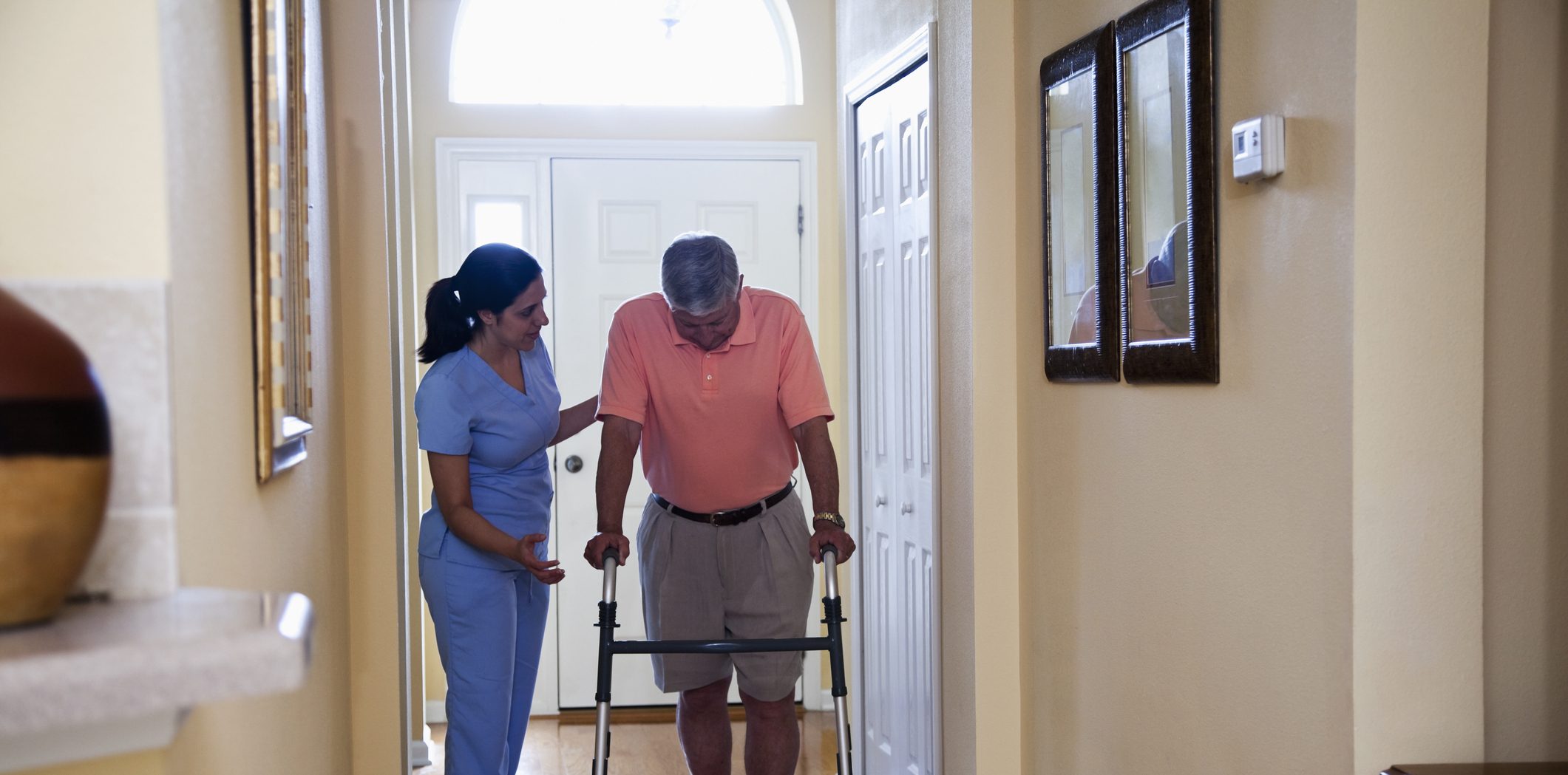 a home nurse walking along side a patient using a walker