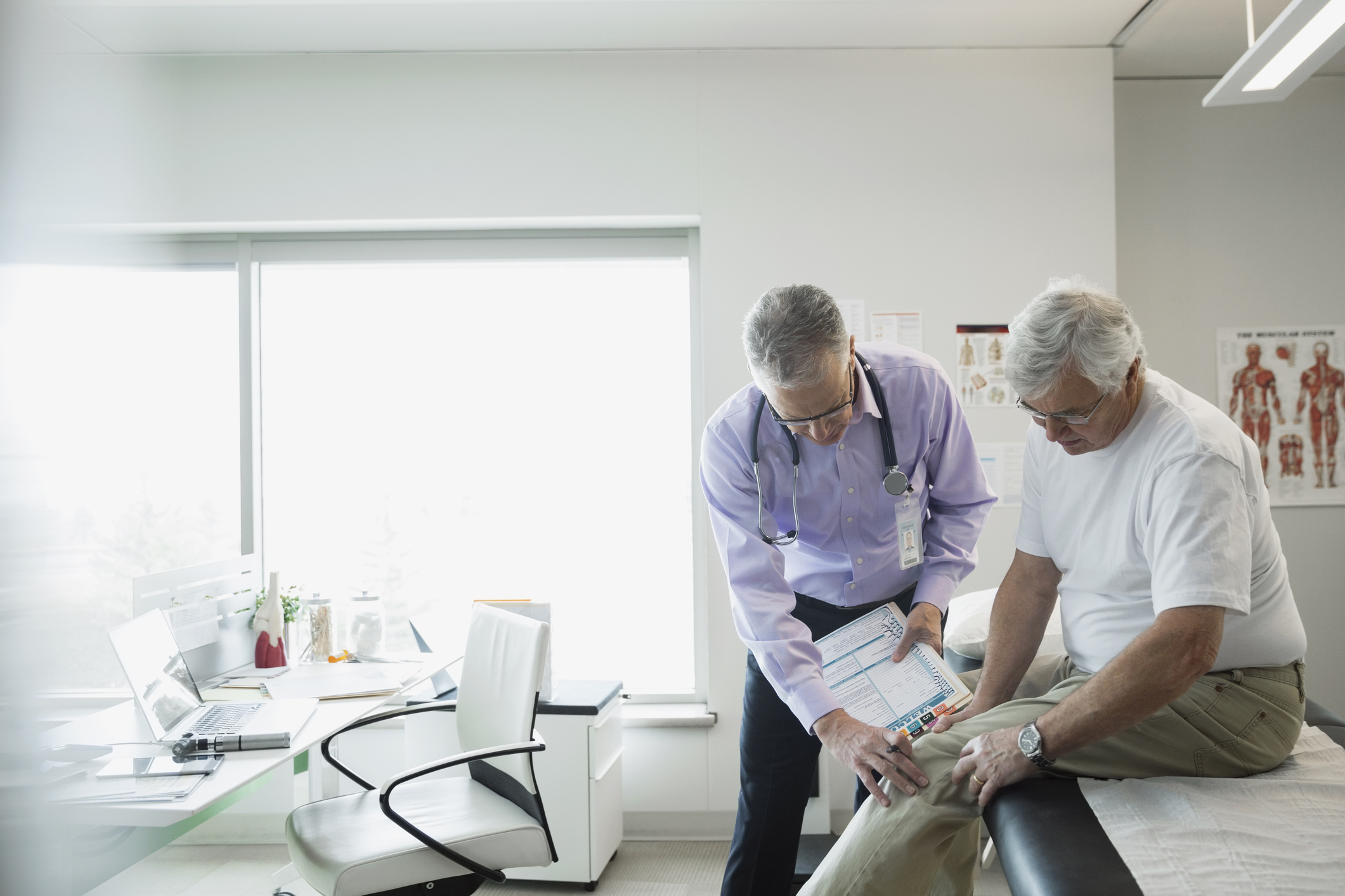 Doctor examining a patient's knee during a check-up in a medical office.